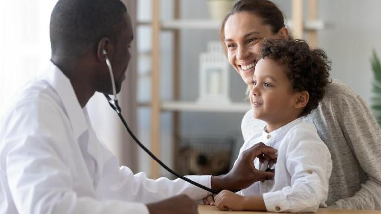 A pediatrician listens to a young patient's heartbeat.