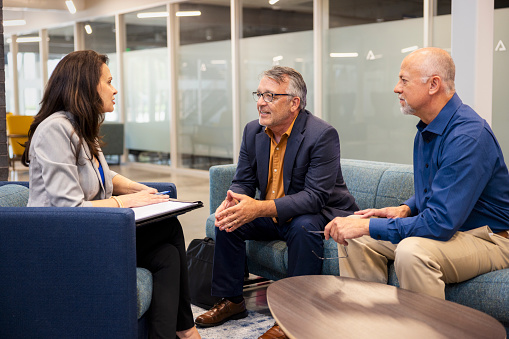 two people sitting and conversing together while interacting with a third person, consider a mediator