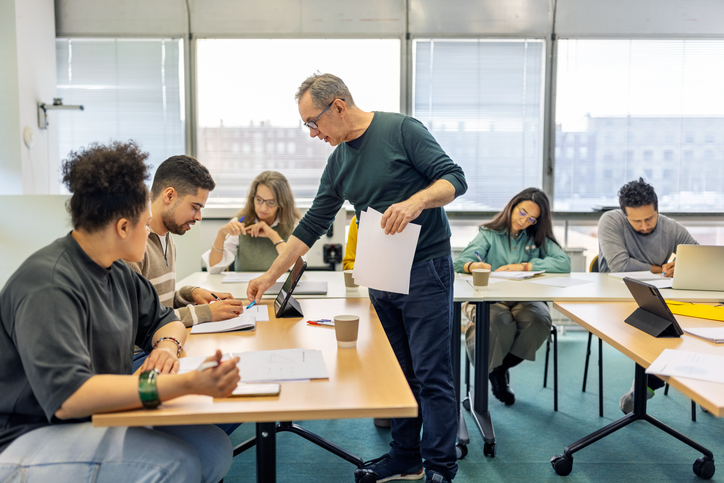 group of people at tables working on a worksheet activity while a presenter guides them