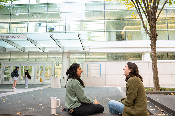 two students sitting on a bench, talking and laughing