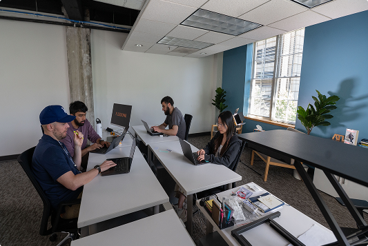 Students on laptops at a large table