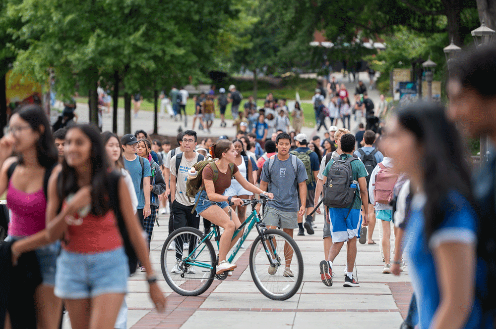 georgia tech students walking and riding bikes down the sidewalk.