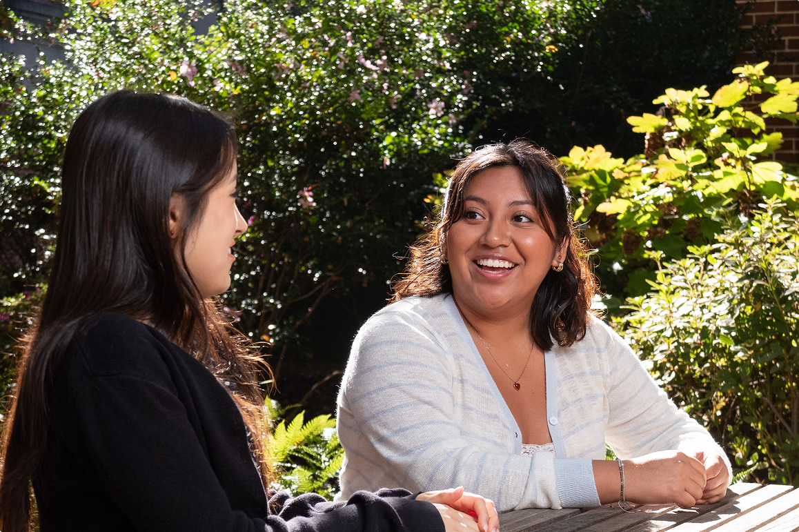Two women sitting outside, talking and smiling