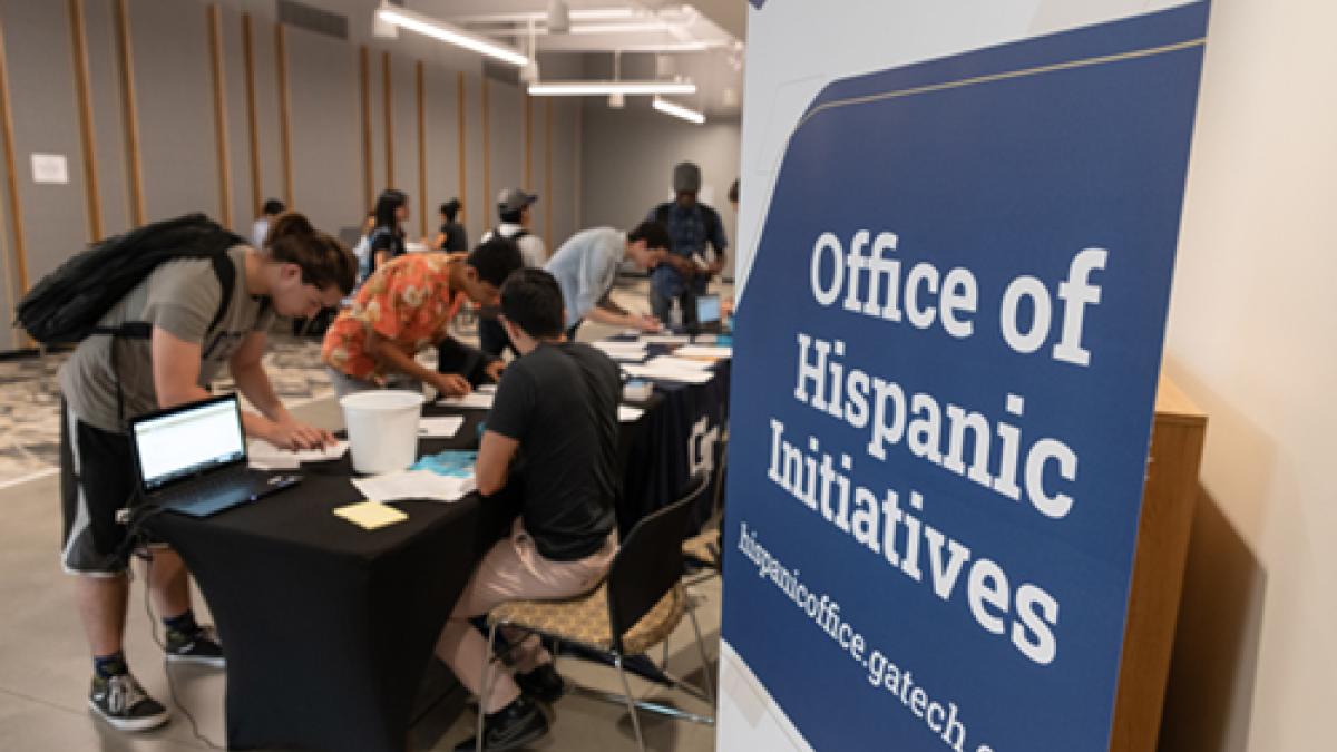 Office of Hispanic Initiatives sign near registration tables.