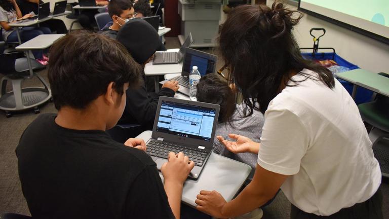 Student and teacher using laptop