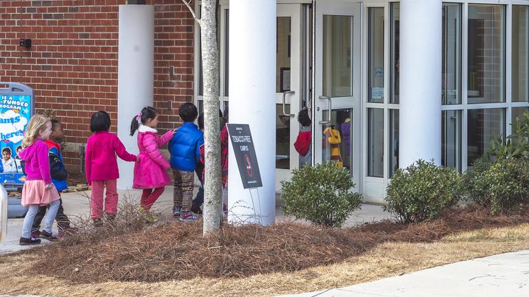 Kids in a line entering a building.