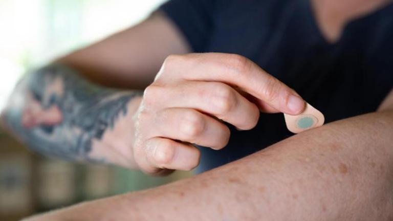 A microneedle patch tattoo is pressed to the skin.
