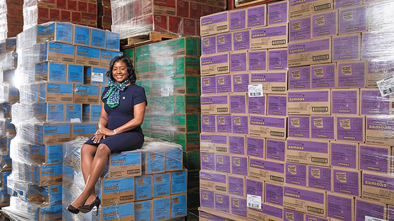 Alantria Dixon, EE 02, sitting on and with dozens of boxes of Girl Scouts' cookies.