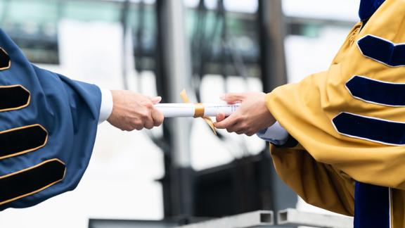  Georgia Tech president hands a ceremonial degree scroll to a new graduate. 