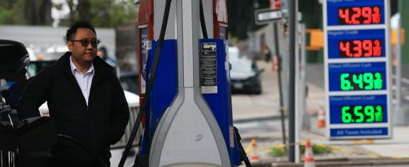 A person filling gas in his car with the gas prices shown in the foreground