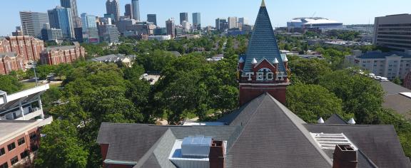Aerial view of Georgia Tech’s historic campus in Atlanta, with the Tech Tower prominently in the foreground and the Atlanta skyline visible in the background under a clear blue sky.