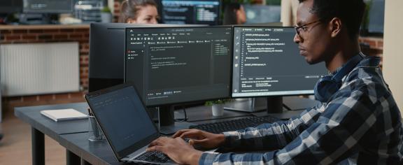 man sitting at computer doing programming. 