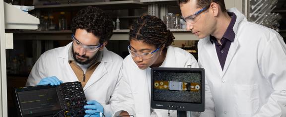 Ramy Ghanim, Joy Jackson, and Alex Abramson test a tiny implantable device in the lab.