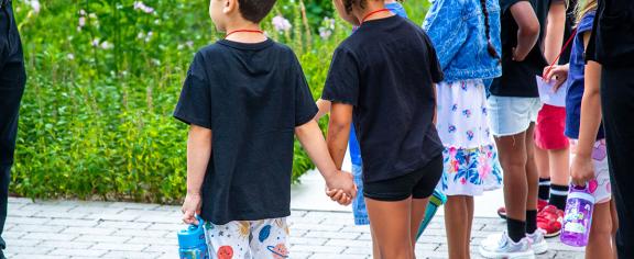 preschool-aged children hold hands and observe as they learn about composting.
