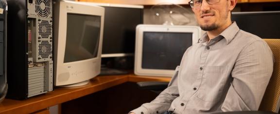 Zsolt Kira sitting in office chair surrounded by old computers