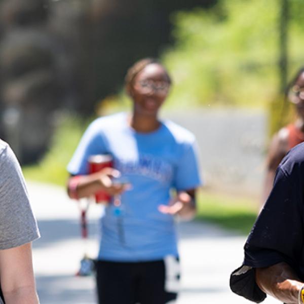 A student wearing a "Serve-Learn-Sustain" tee shirt walks along a campus walkway with a Georgia Tech faculty member.&nbsp;Photo Credit Ben Gray, AJC.

