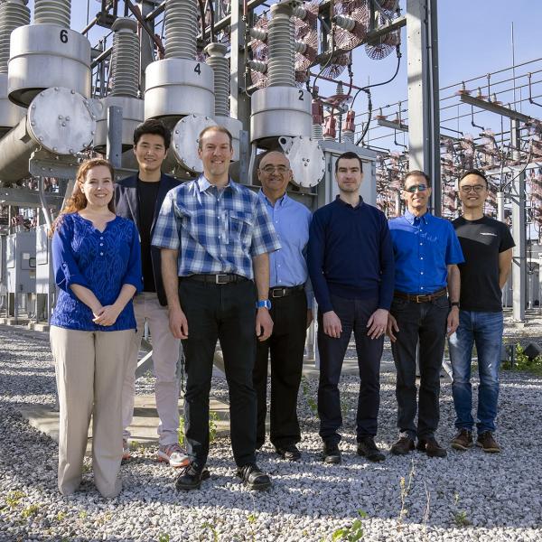 The TESLA (Tough and Ecological Supercritical Line Breaker for AC) team in front of high-voltage circuit breakers. 