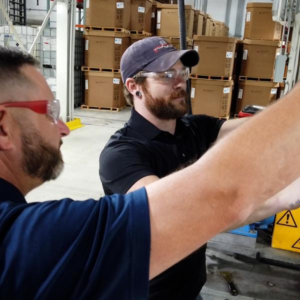 Lead technician, Austin Hicks, taps on a monitoring screen while his co-worker looks on at the manufacturing facility for Silon in Peachtree City, Georgia
