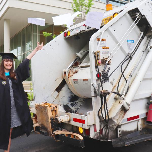 image of Emma Brodzik in master's garb with recycling truck